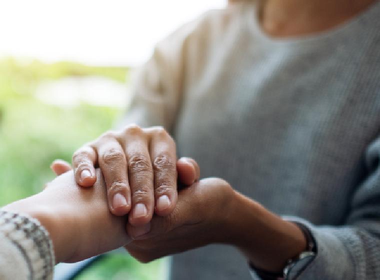 Twee mensen die elkaars hand vasthouden als steun