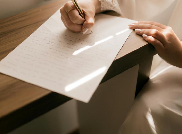 Vrouw schrijft met de hand een brief aan een bureau