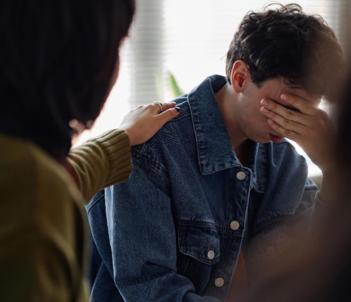 Iemand legt een hand op de schouder van een emotionele man