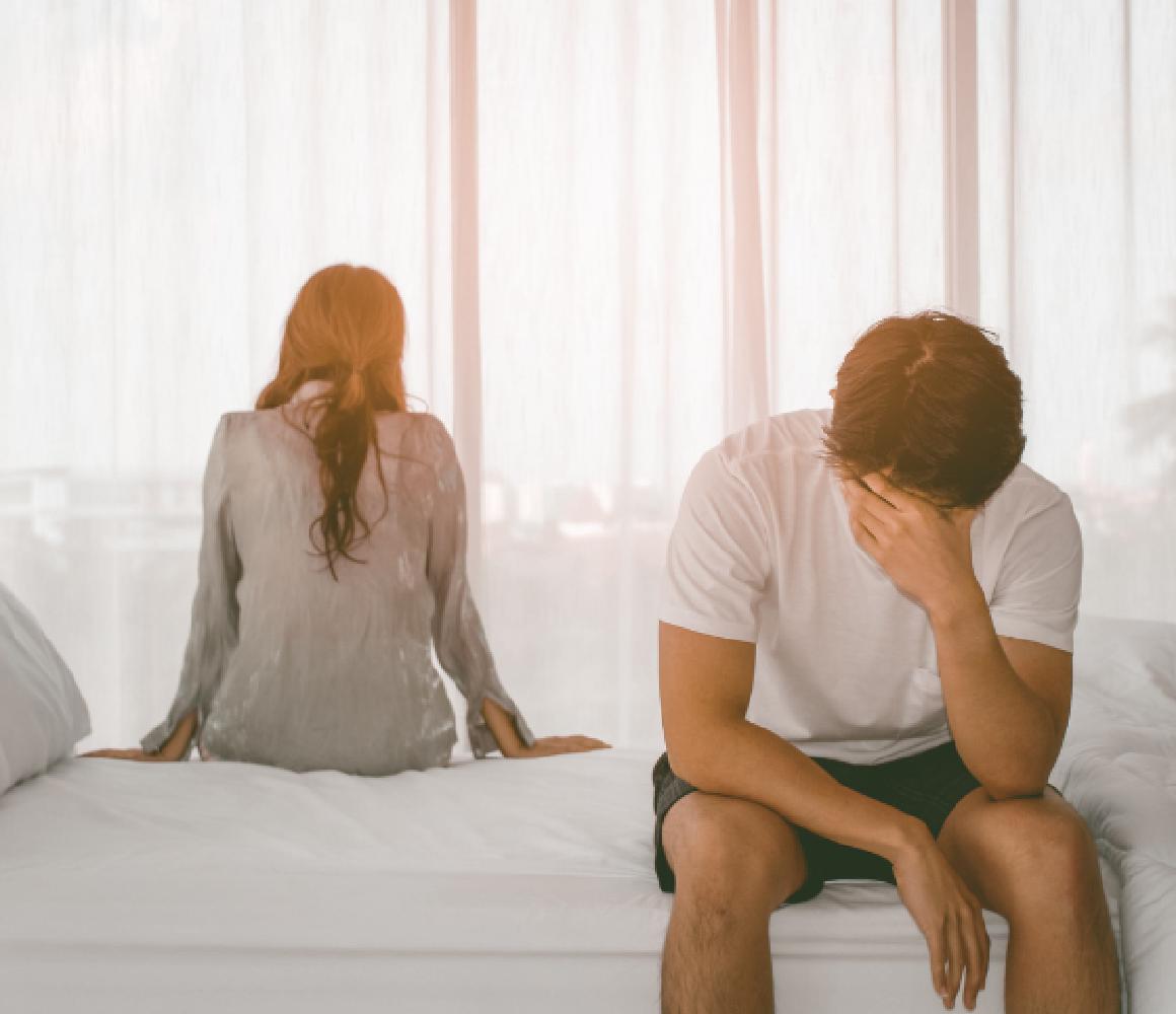 Man en vrouw zitten met de rug naar elkaar op bed