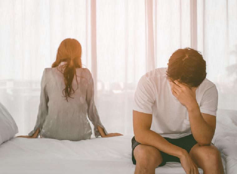 Man en vrouw zitten met de rug naar elkaar op bed