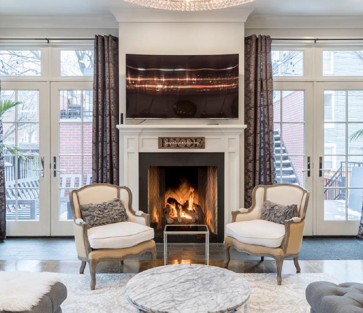Woonkamer met brandende open haard en twee crème fauteuils