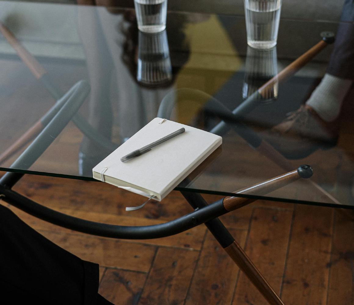 Notitieboekje en pen op een glazen tafel tijdens een gesprek