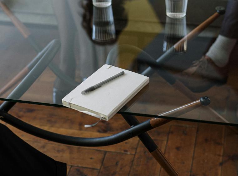 Notitieboekje en pen op een glazen tafel tijdens een gesprek
