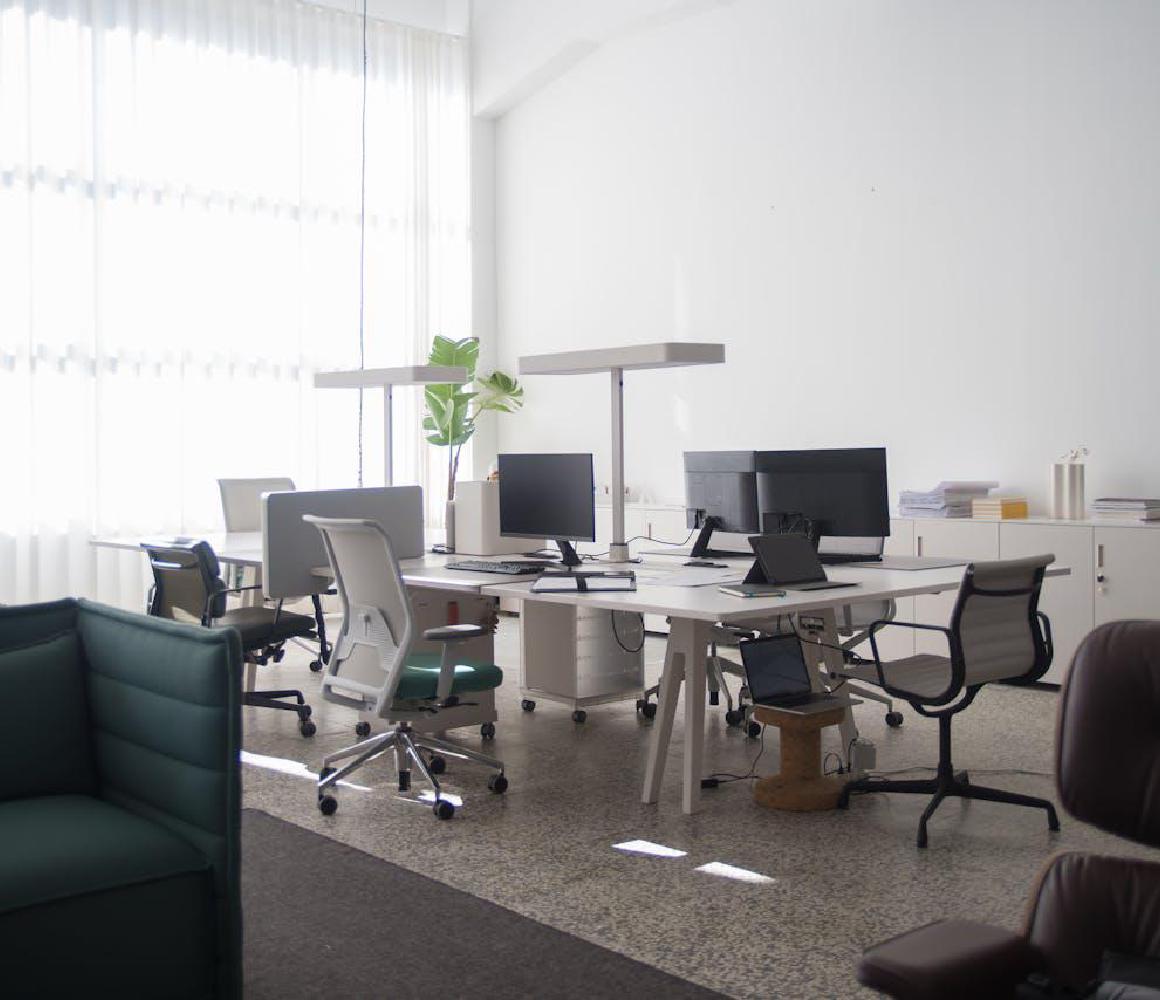 Leeg modern kantoor met bureaus, beeldschermen en bureaustoelen
