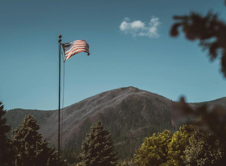 Amerikaanse vlag wappert voor een bebost bergmassief