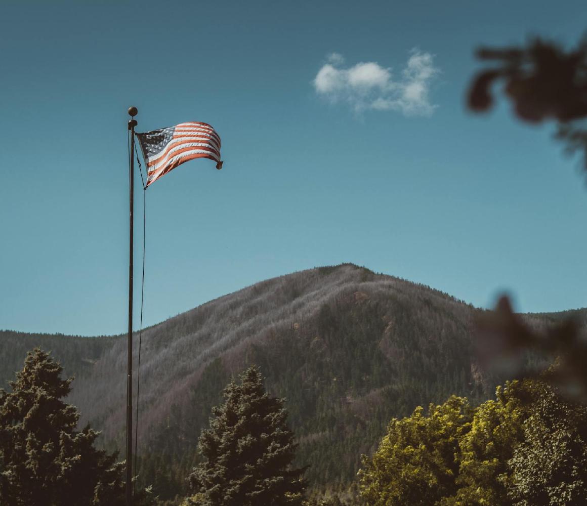 Amerikaanse vlag wappert voor een bebost bergmassief