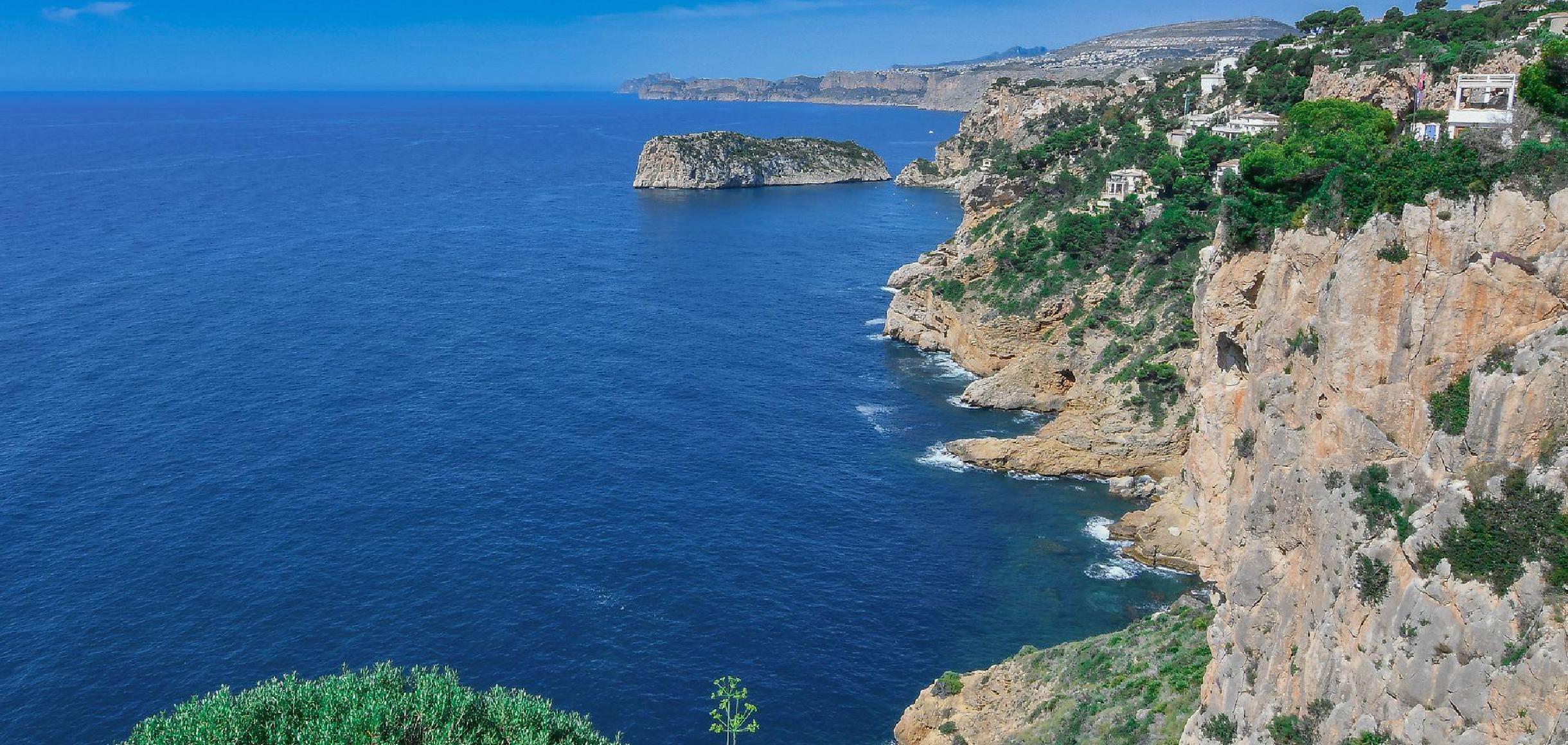 Rotsachtige mediterrane kustlijn met villa's op de klif