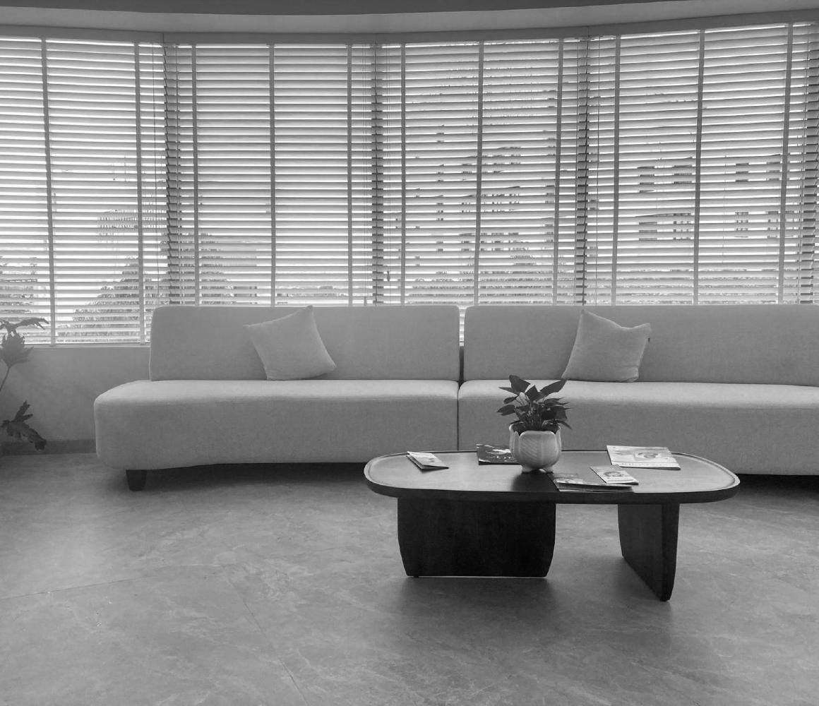 Wachtruimte met bank en ovale salontafel voor jaloezieramen, zwart-wit