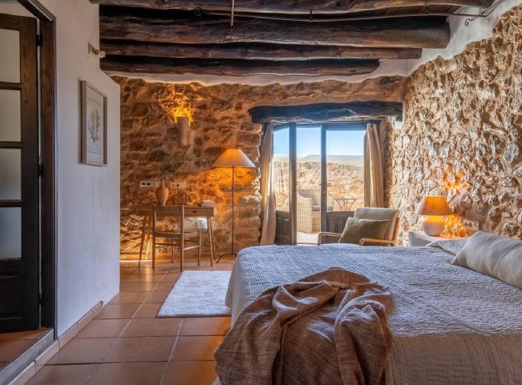 Slaapkamer met stenen muren en balkon met zeezicht bij Ibiza Calm