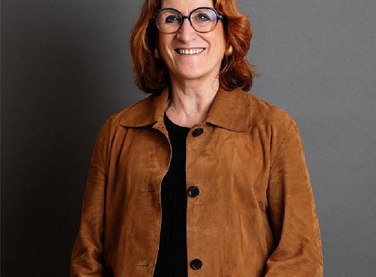 Carien glimlachend met bril en bruine suède jas
