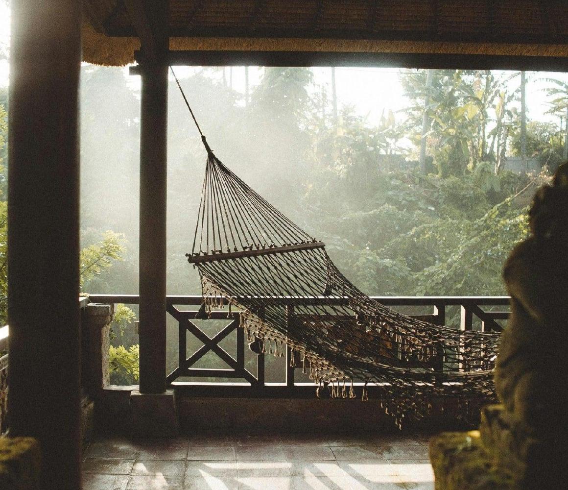 Hangmat op een overdekt terras met uitzicht op een bosrijke omgeving